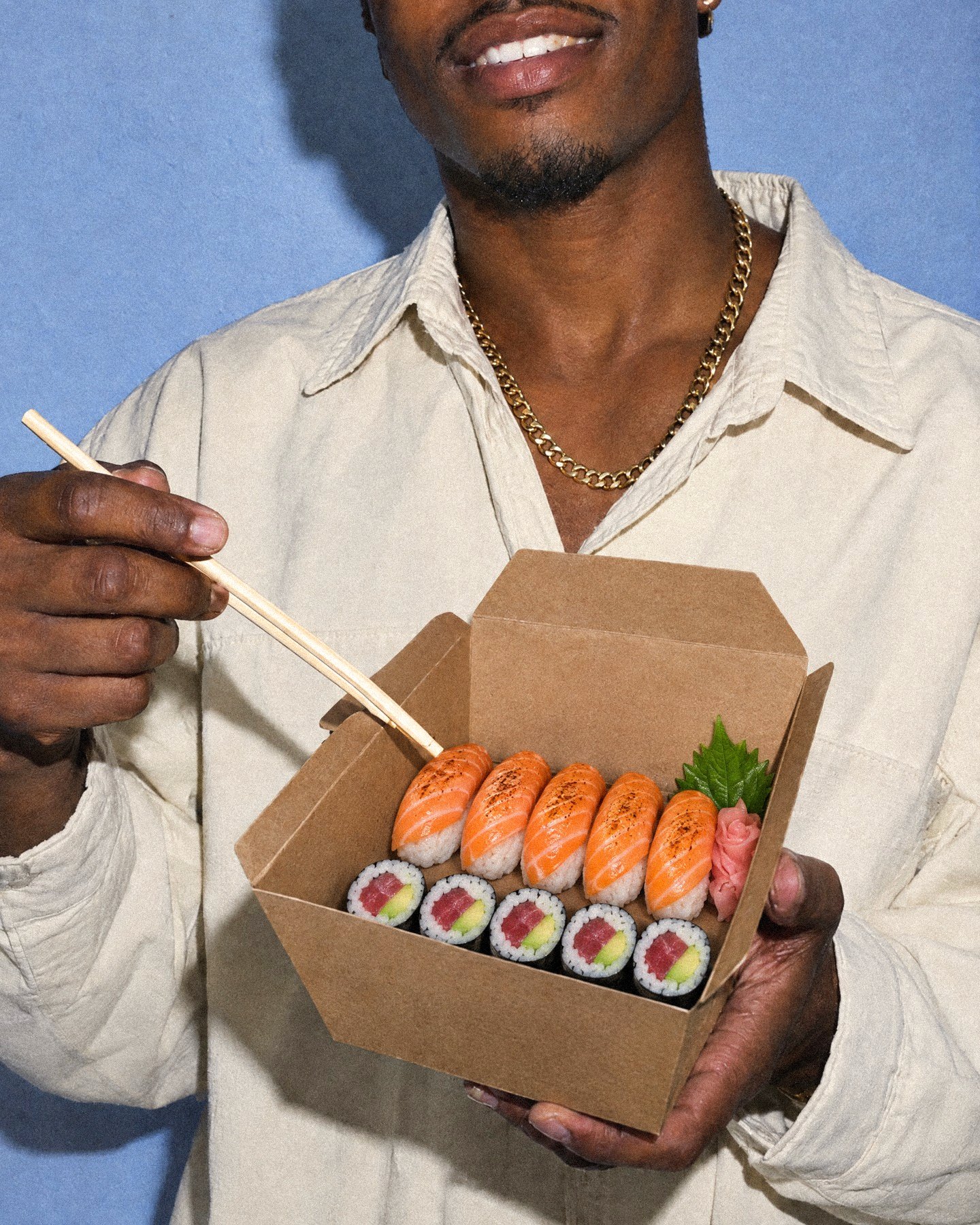 A guest holding an open carryout box of torched sushi